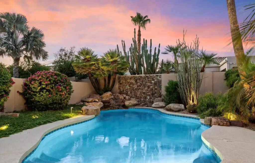 Backyard oasis pool with rock waterfall and cactus garden.