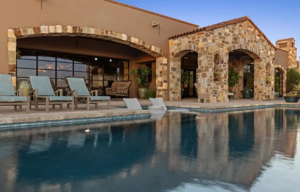 Stone-arched home with luxury pool and lounge seating.