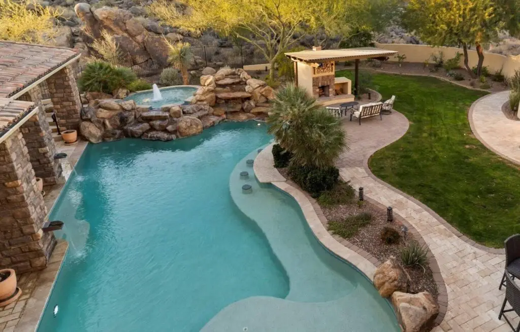 Backyard pool with rock waterfall and outdoor fireplace patio.