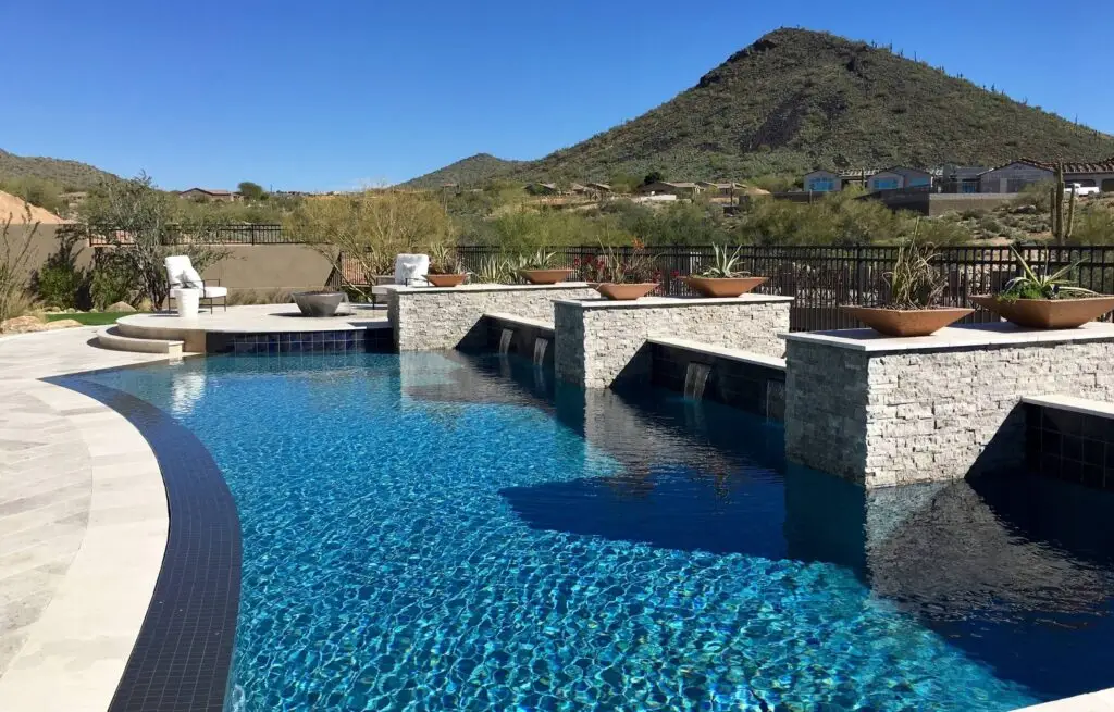 Desert backyard pool with waterfalls and stone planters.