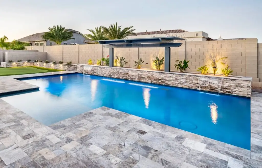 Backyard pool with pergola, waterfall, and tropical landscaping.