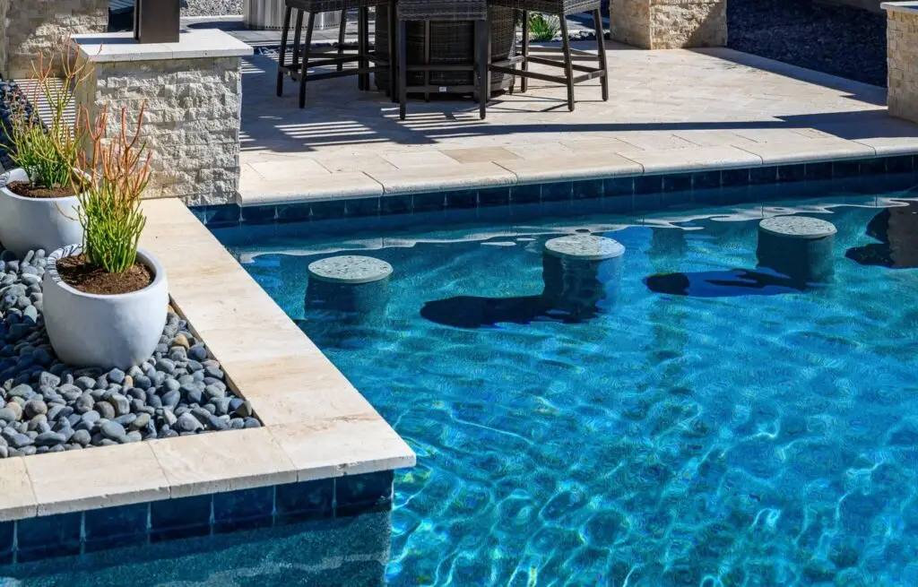 Modern pool with in-water bar seating and stone pool deck.