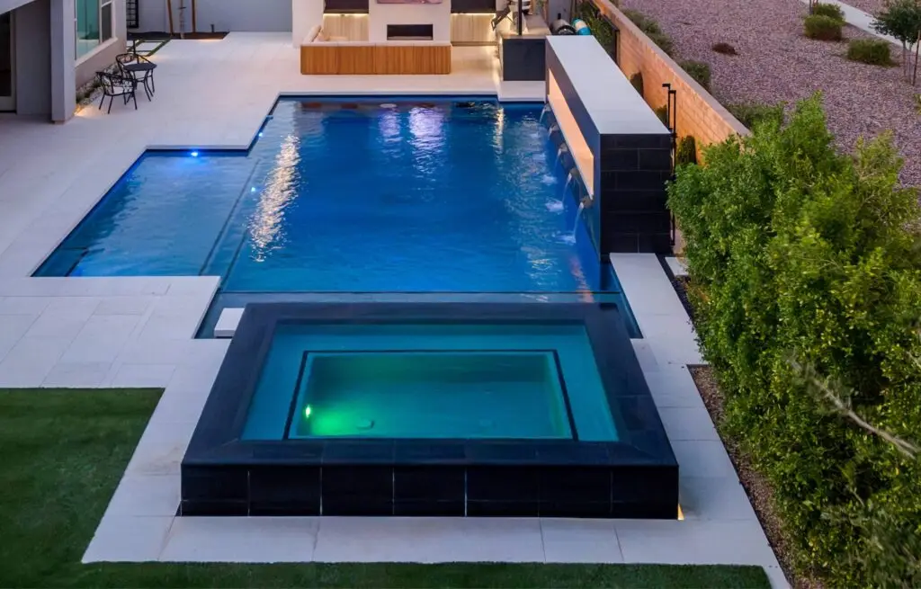 Contemporary backyard pool with black-tile spa and fire feature.