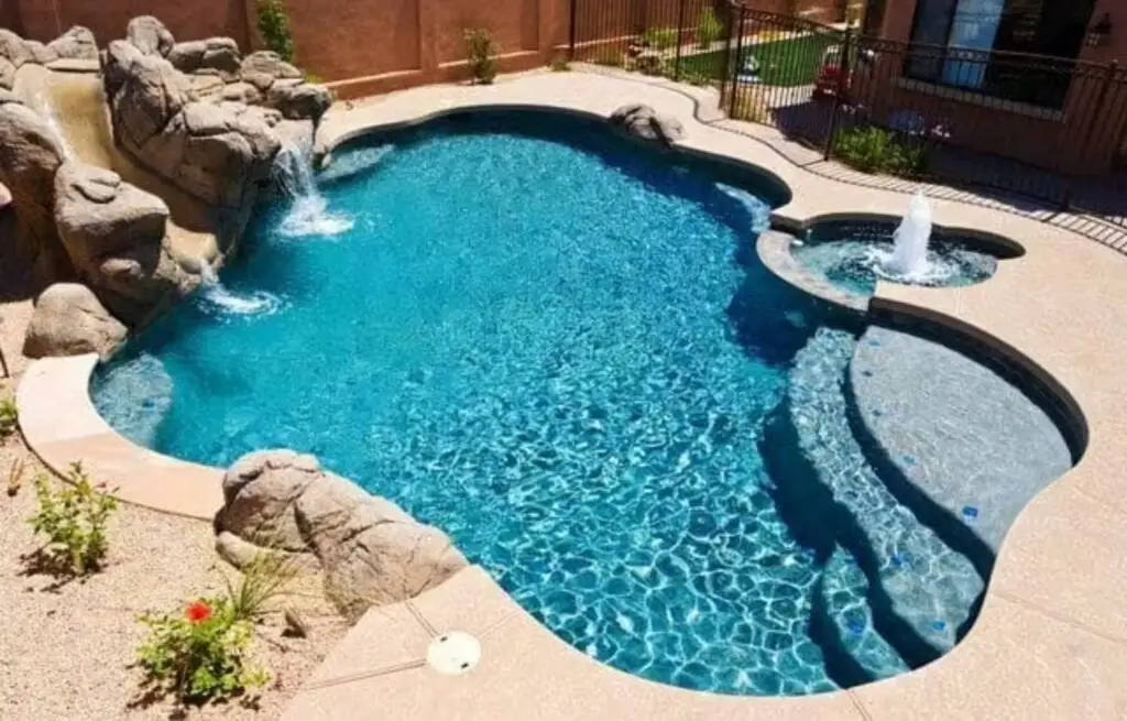 Backyard rock pool with slide, waterfall, and attached spa.