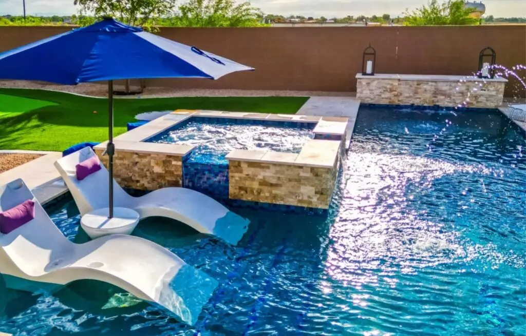 Pool with tanning ledge loungers and blue umbrella.