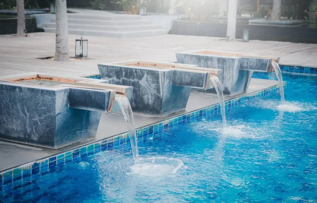 Modern pool with sleek metal water bowls and blue tile.