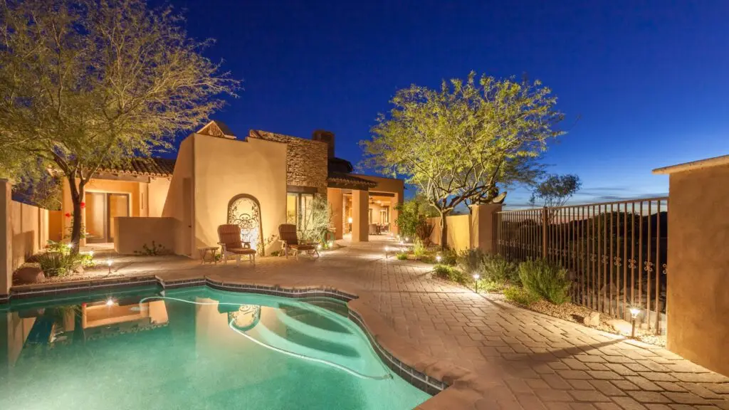 Desert-style home with pool lighting at night.